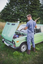 A person fixing a van engine outdoors with tools spread around.