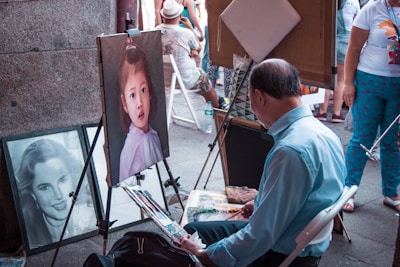 An artist delicately painting a portrait while observing a seated model in the studio.