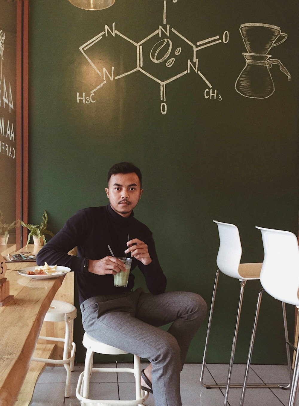 man sitting on chair while holding glass cup