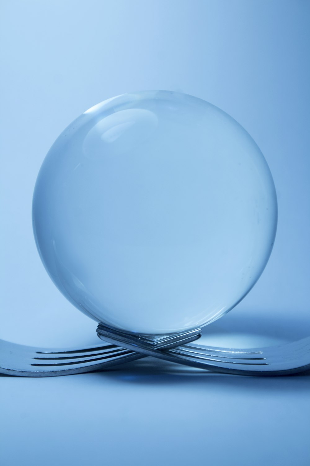 clear glass ball on top of two forks