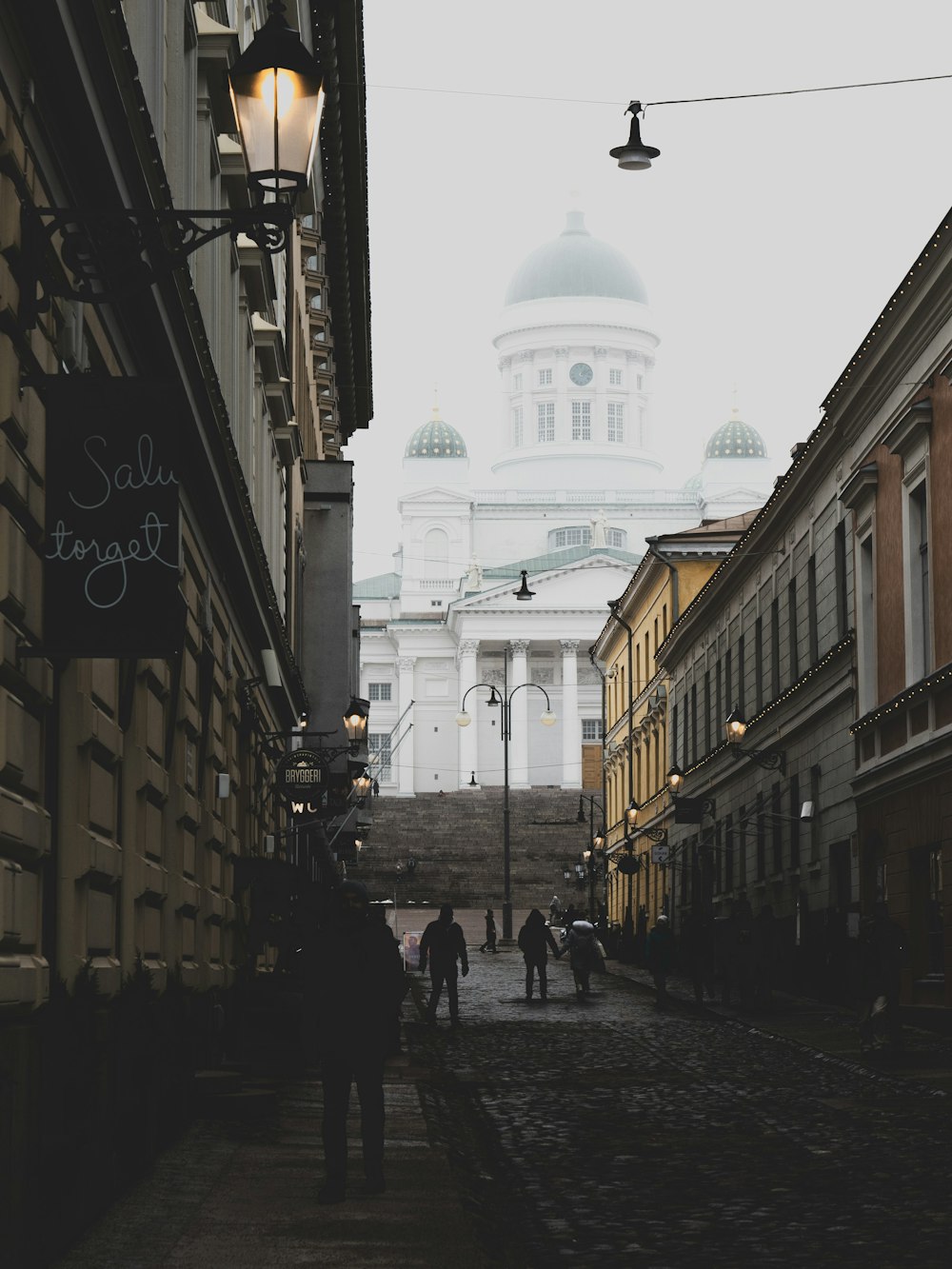 people walking between brown buildings