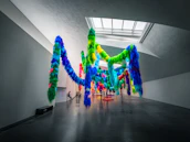 Wide shot of an exhibition space featuring diverse sculptures and string art installations