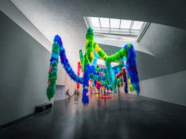Wide shot of an exhibition space featuring diverse sculptures and string art installations