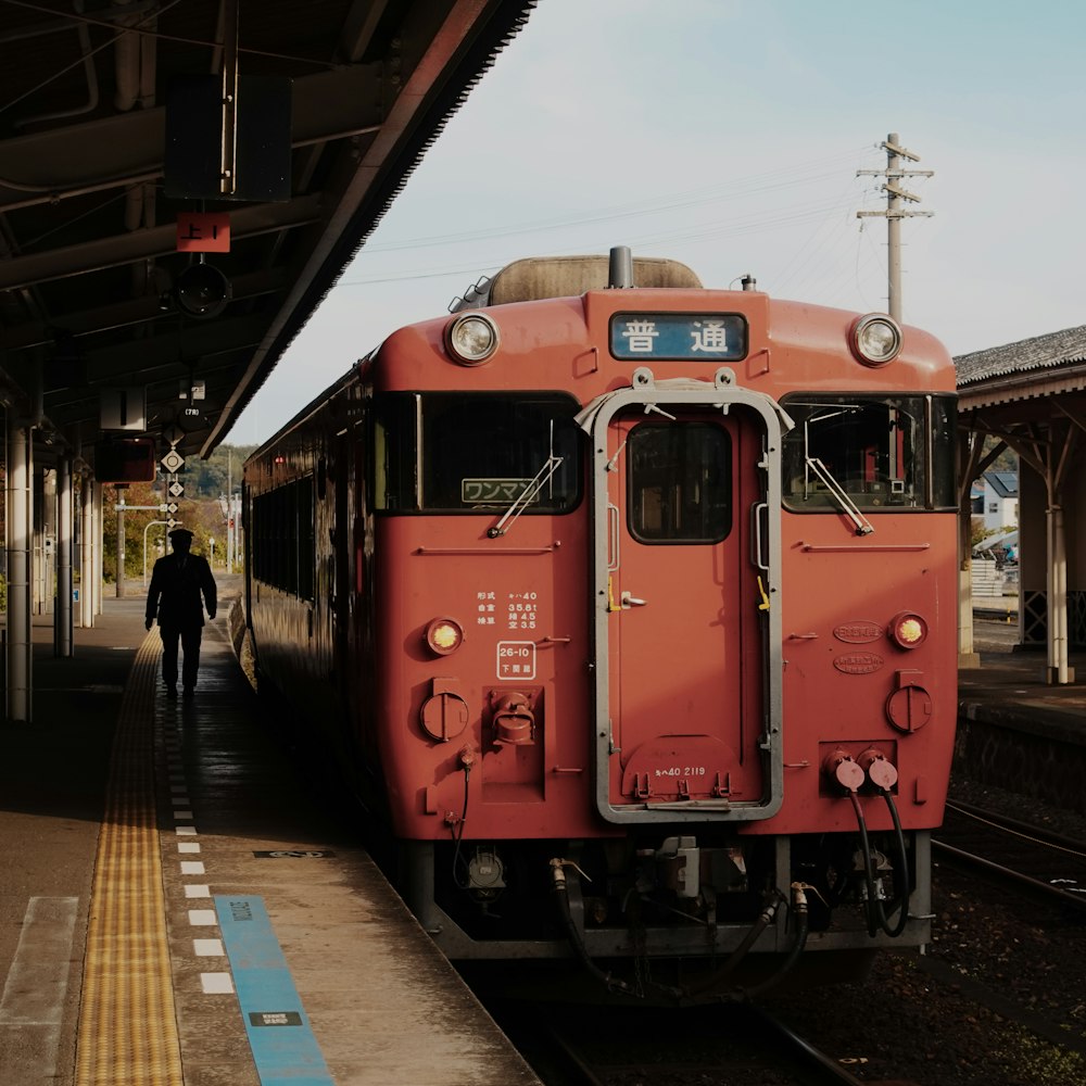 red train beside station during daytime