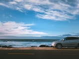 Shiny white SUV on a coastal road with ocean backdrop.