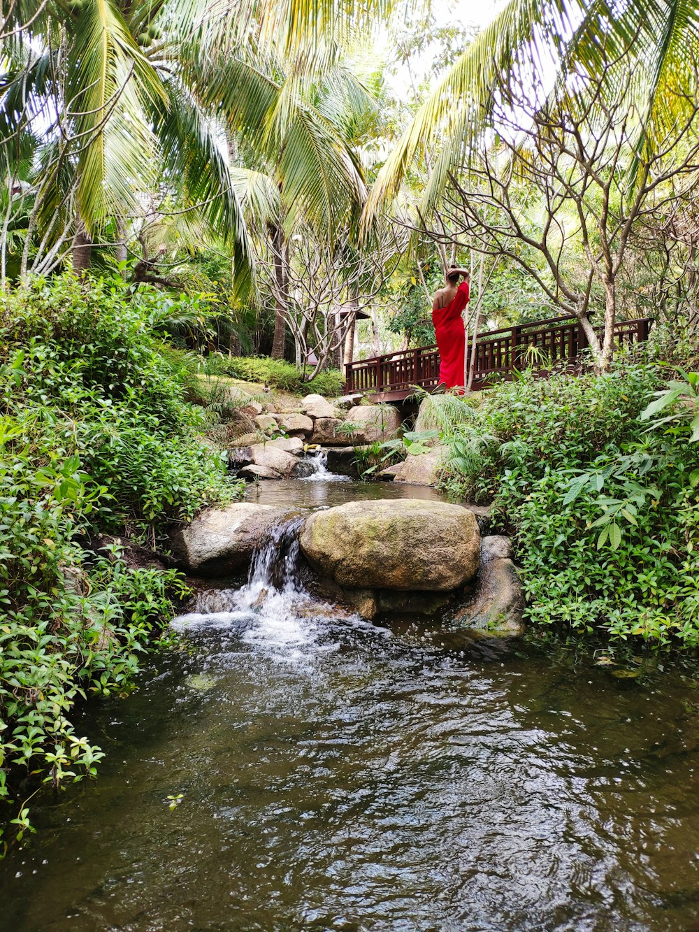 person in red dress standing near water pond