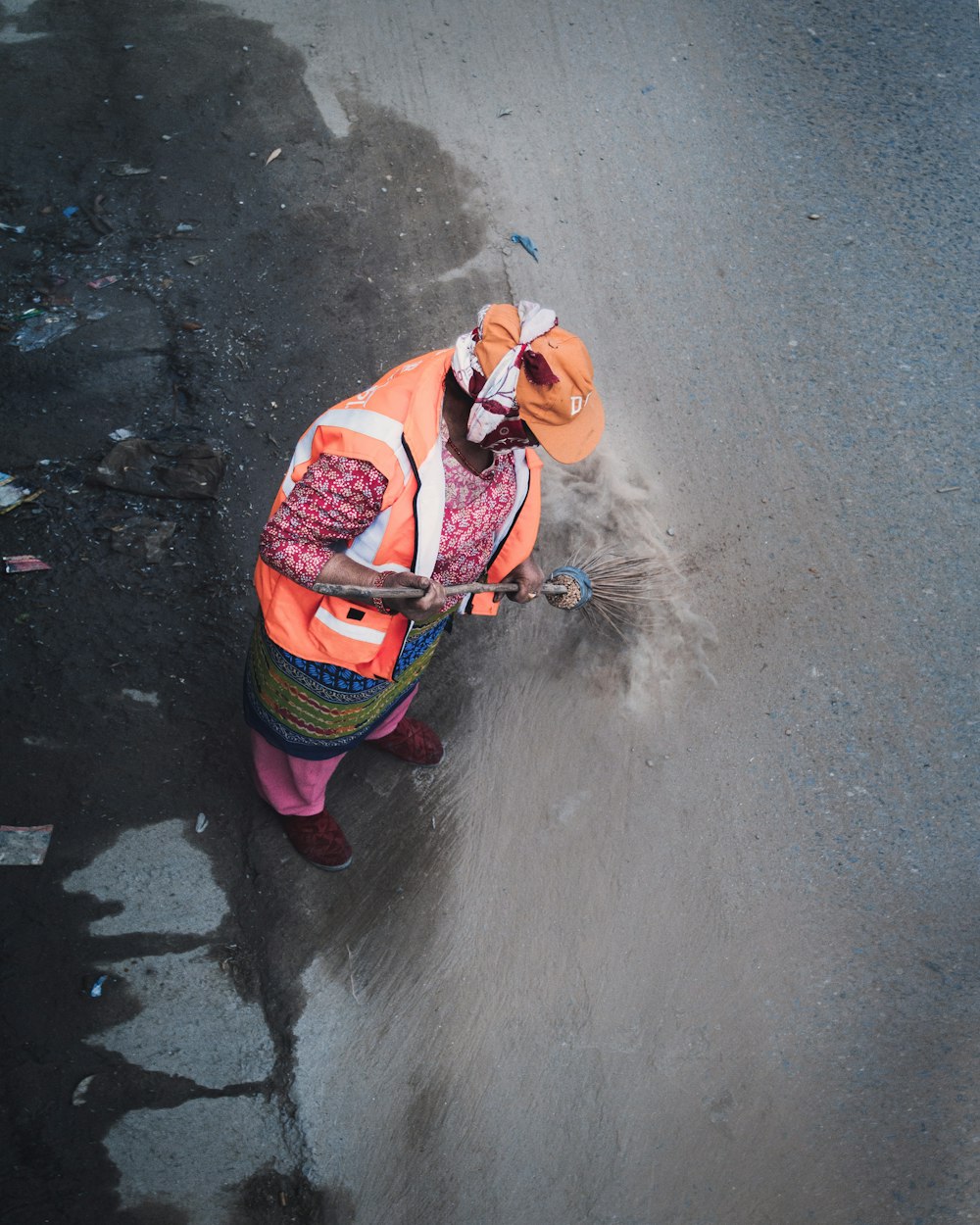 person wearing orange vest standing on grey surface