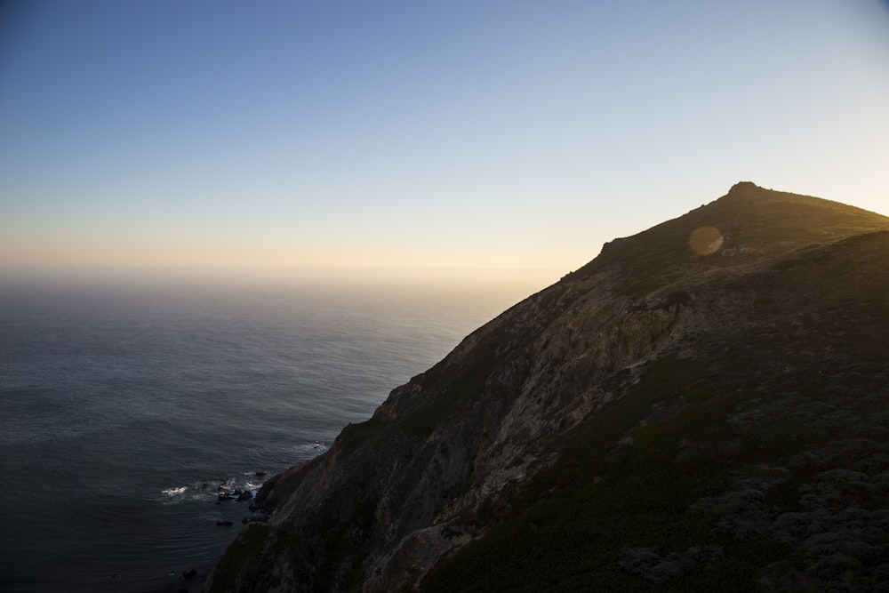 aerial photography of mountain beside sea under blue sky