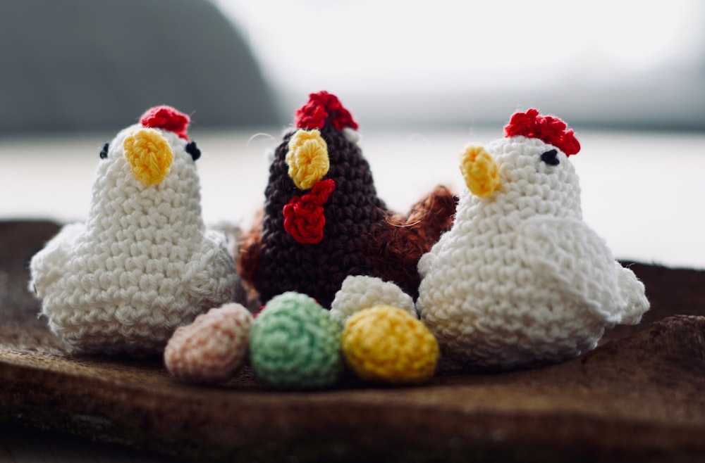 three knit chicken figures on brown wood
