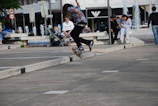 Sentra Skate team member performing a kickflip trick on a city street with cheering onlookers.