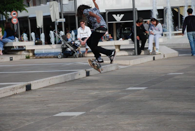 Sentra Skate team member performing a kickflip trick on a city street with cheering onlookers.