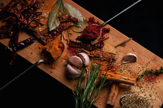 Close-up of fresh herbs and spices arranged neatly on a wooden cutting board.