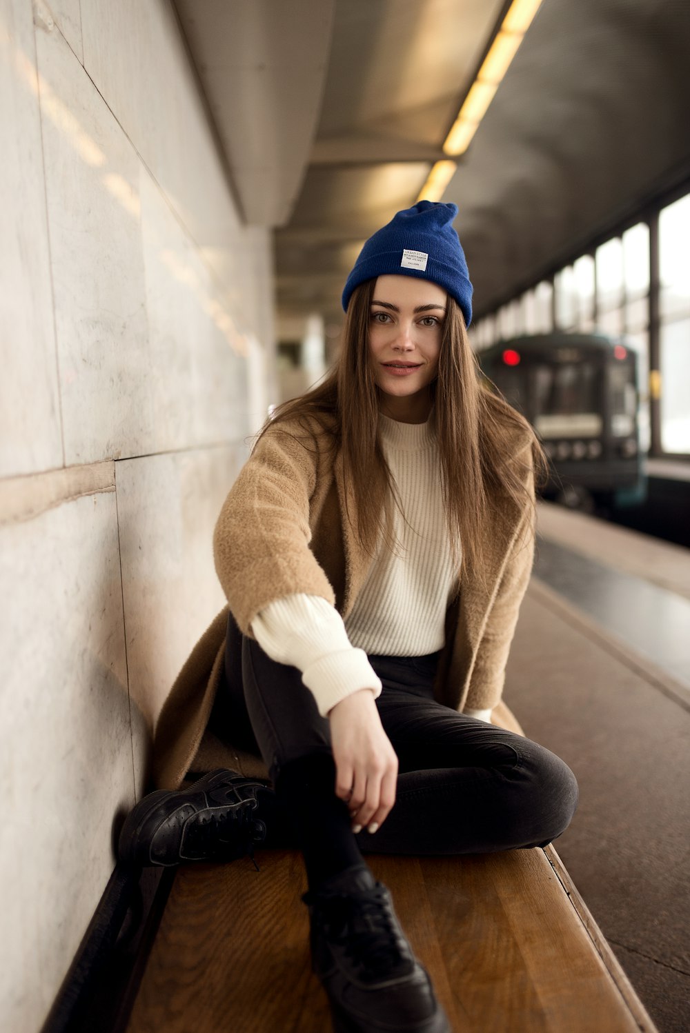 woman wearing beige sweater and black pants sitting on bench