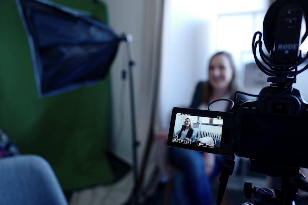 a woman sitting in front of a green screen