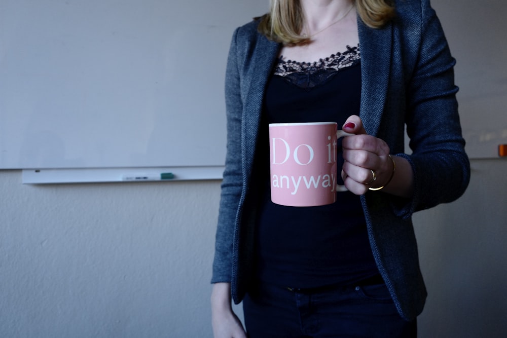 woman in gray blazer holding pink and white ceramic coffee mug