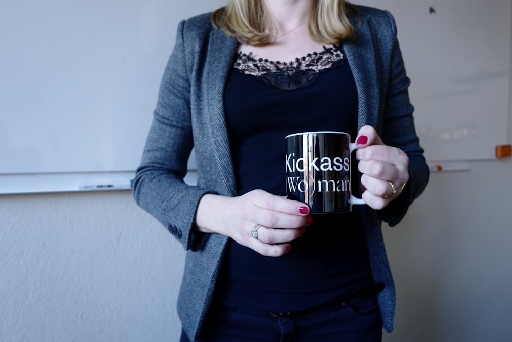 woman wearing blue cardigan holding black mug