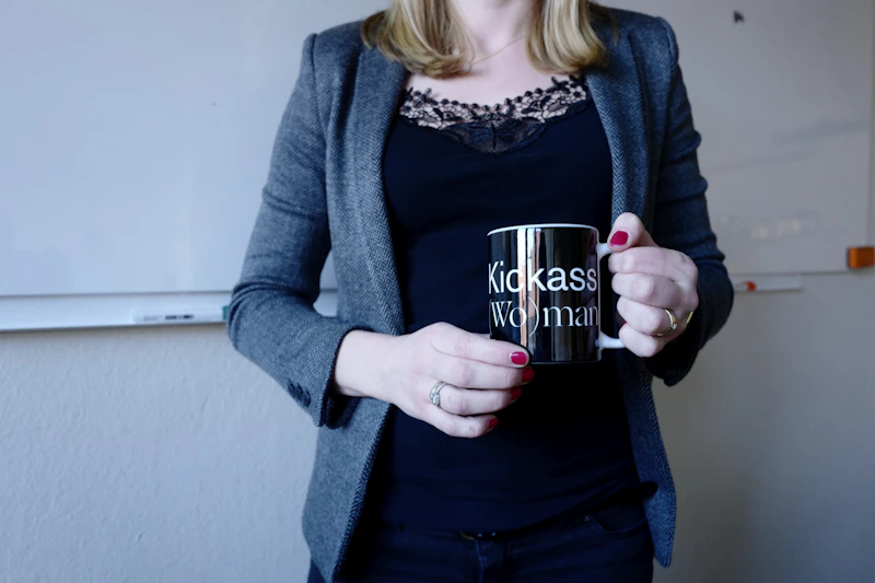 woman in blue cardigan holding a black mug