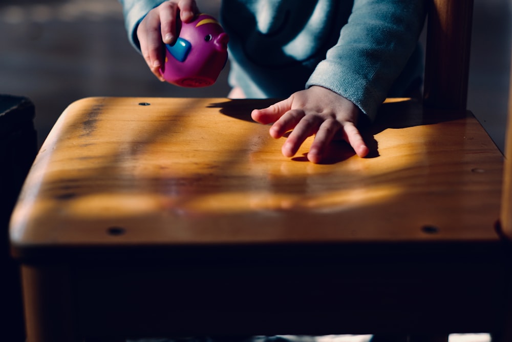 toddler playing on table while holding purple ball