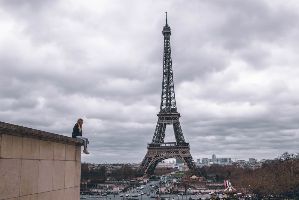 uomo seduto sull'edificio che guarda la Torre Eiffel