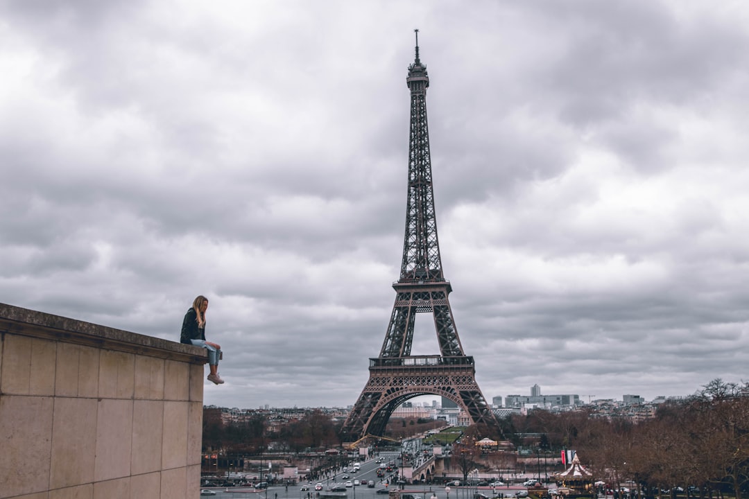 man sitting on the building watching the Eiffel Tower