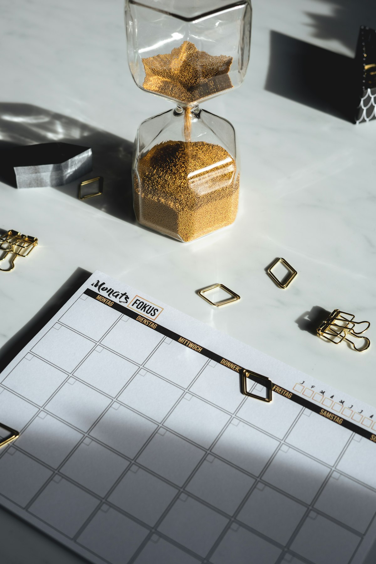 Planer und Sanduhr – Symbolbild für feste Routine und Zeitplan