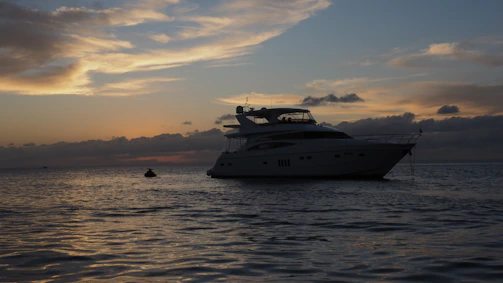 A serene yacht cruising during a vibrant sunset over the Aegean Sea.