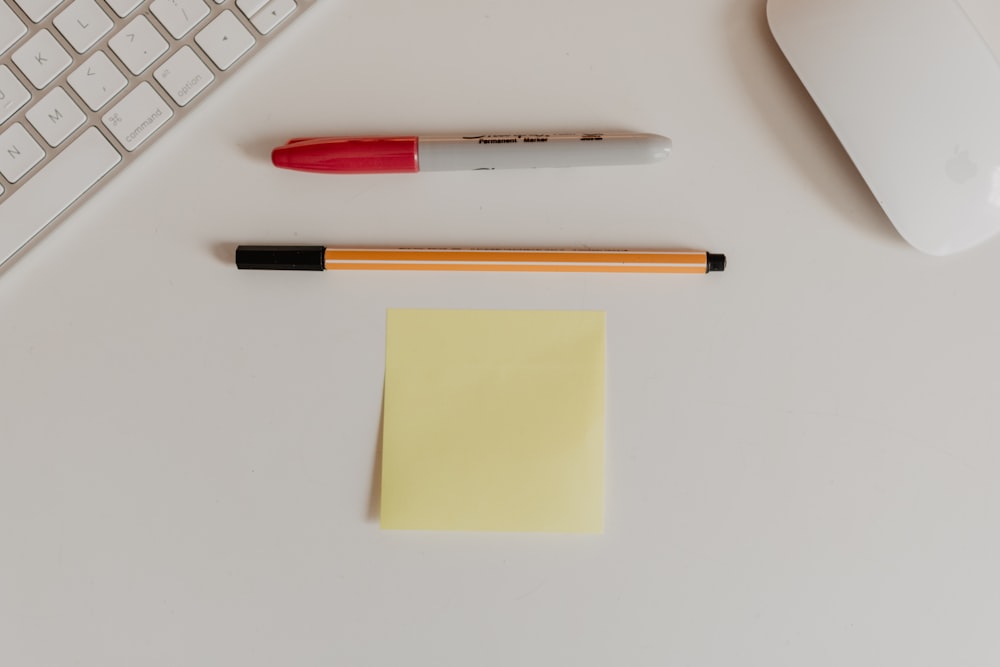 Marqueur rouge et stylo orange sur surface blanche