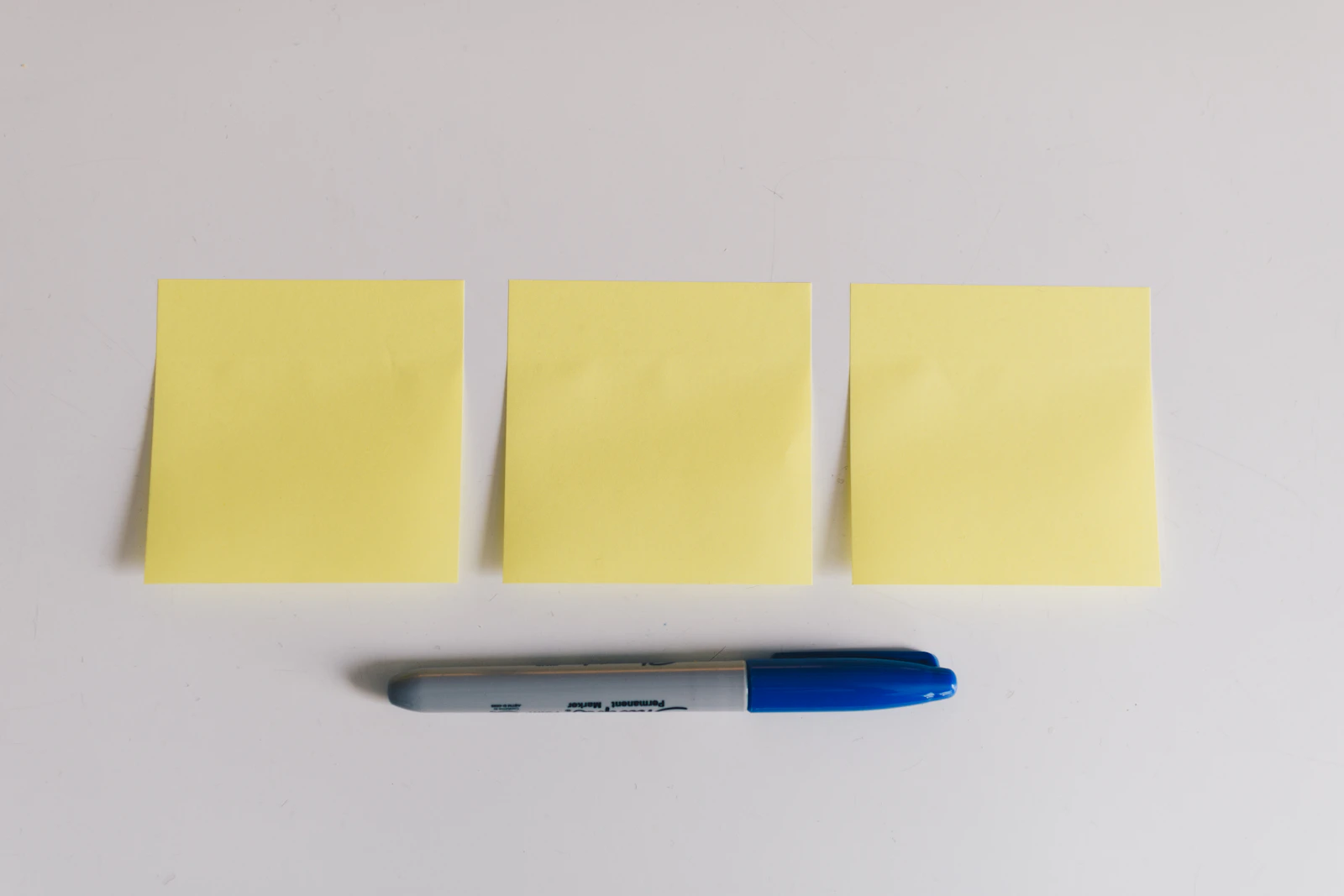 Three blank yellow sticky notes on a white wall