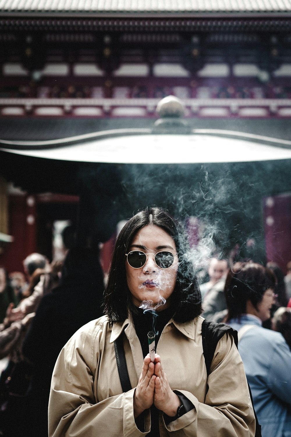 a woman in a trench coat smoking a cigarette
