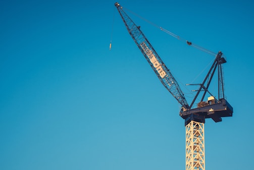 A massive crane towering over a city skyline, framed by a clear blue sky.