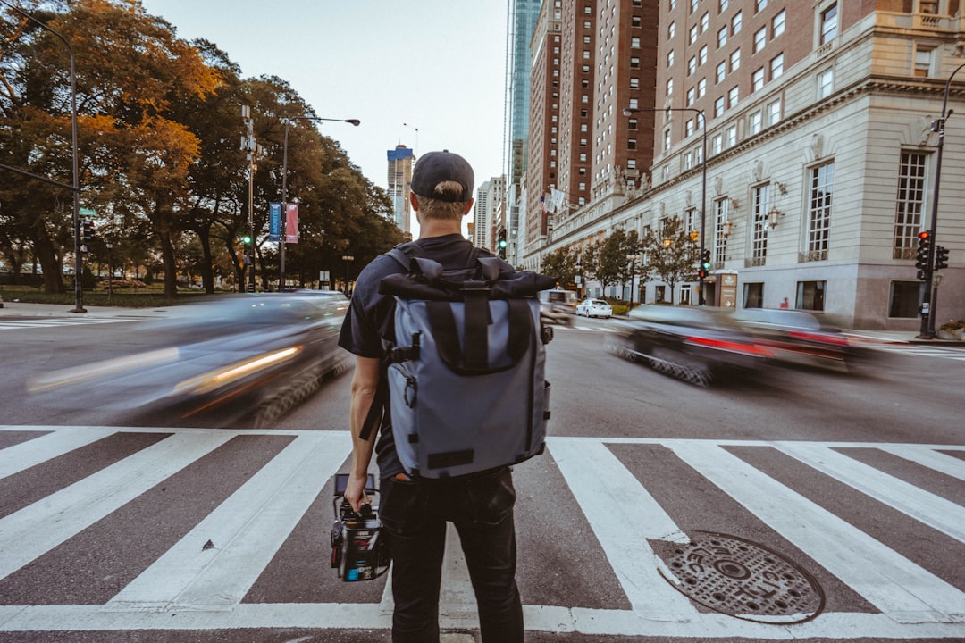 man with backpack standing near pedestrian lane