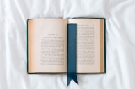 an open book with a blue ribbon on a white sheet