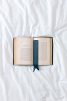 an open book with a blue ribbon on a white sheet