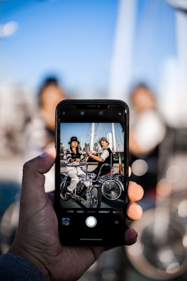 person capturing two person while riding on bicycle
