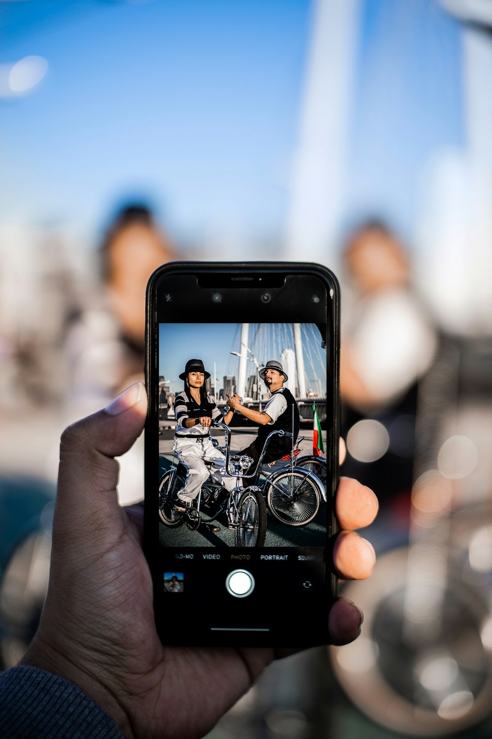 person capturing two person while riding on bicycle