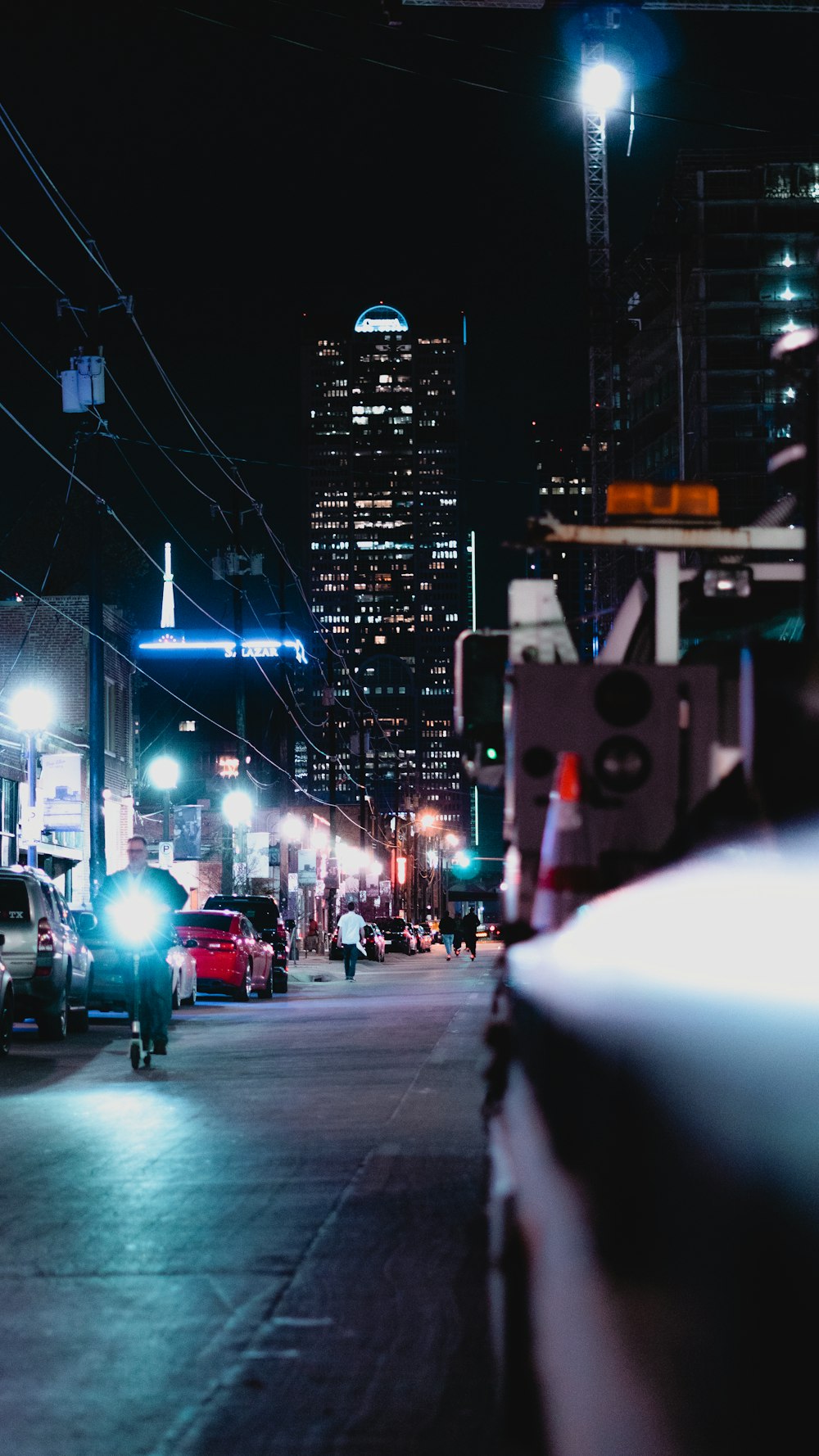 a city street at night with cars parked on the side of the road