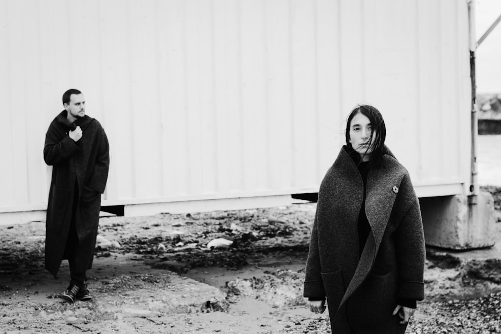 grayscale photography of woman and man standing wearing coat