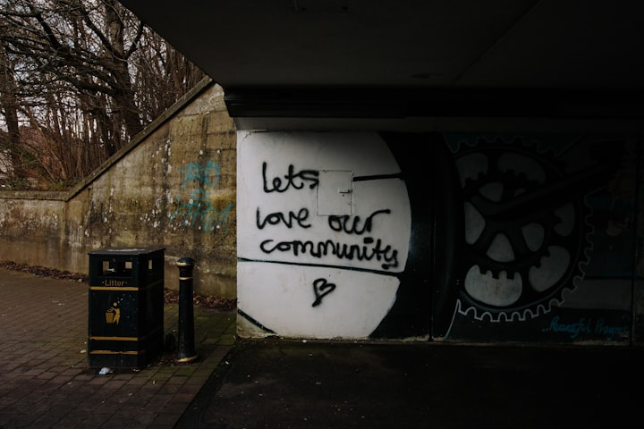 wall art under a overhead road saying "lets love our community" overcast and raining 