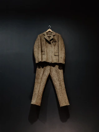 Tailored brown trousers hanging neatly with soft natural light highlighting the texture