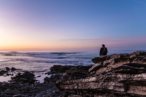 person sitting on cliff