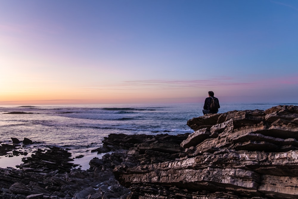 person sitting on cliff