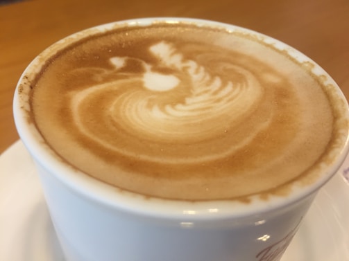 Close-up of a latte art heart being poured into a ceramic cup on the mobile cart.