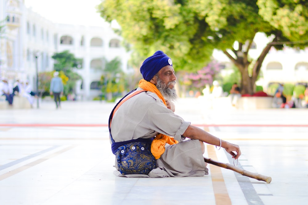 man holding stick sitting pavement