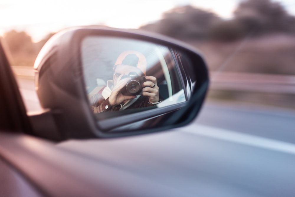 man taking photo outside vehicle window with mirror reflection