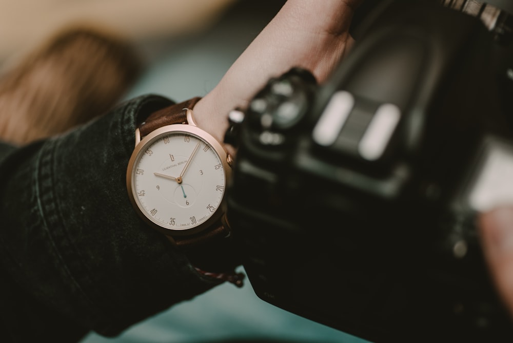 round white and gold-colored analog watch at 10:05