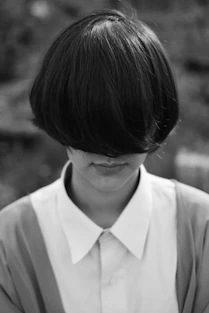 woman with cropped hair covering her face