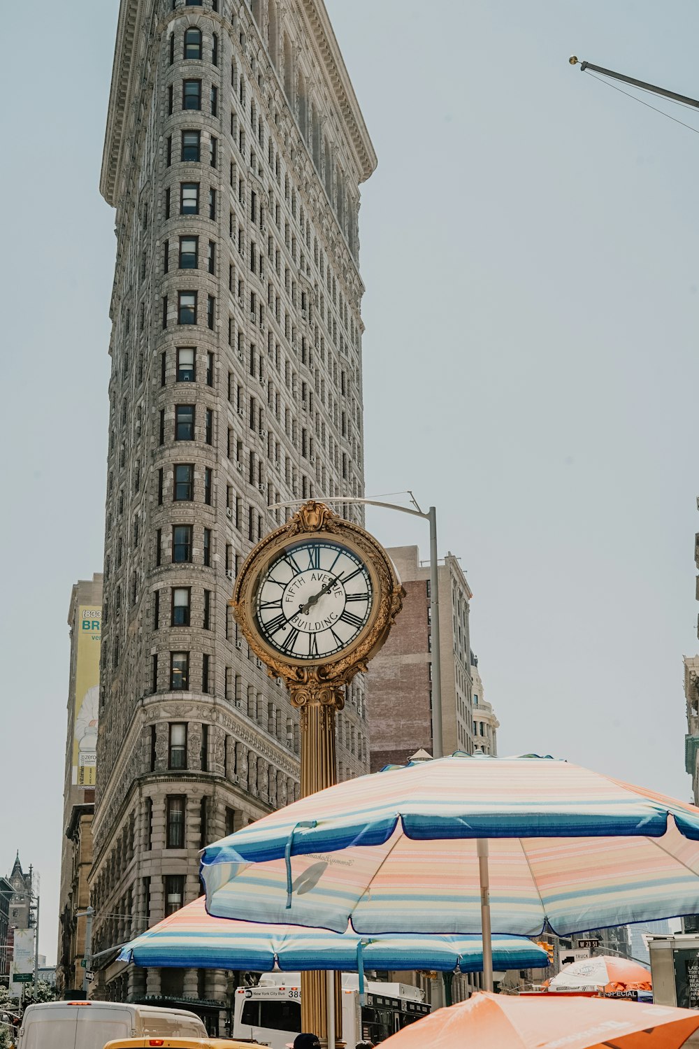 round analog clock near Flatiron building at New York during daytime