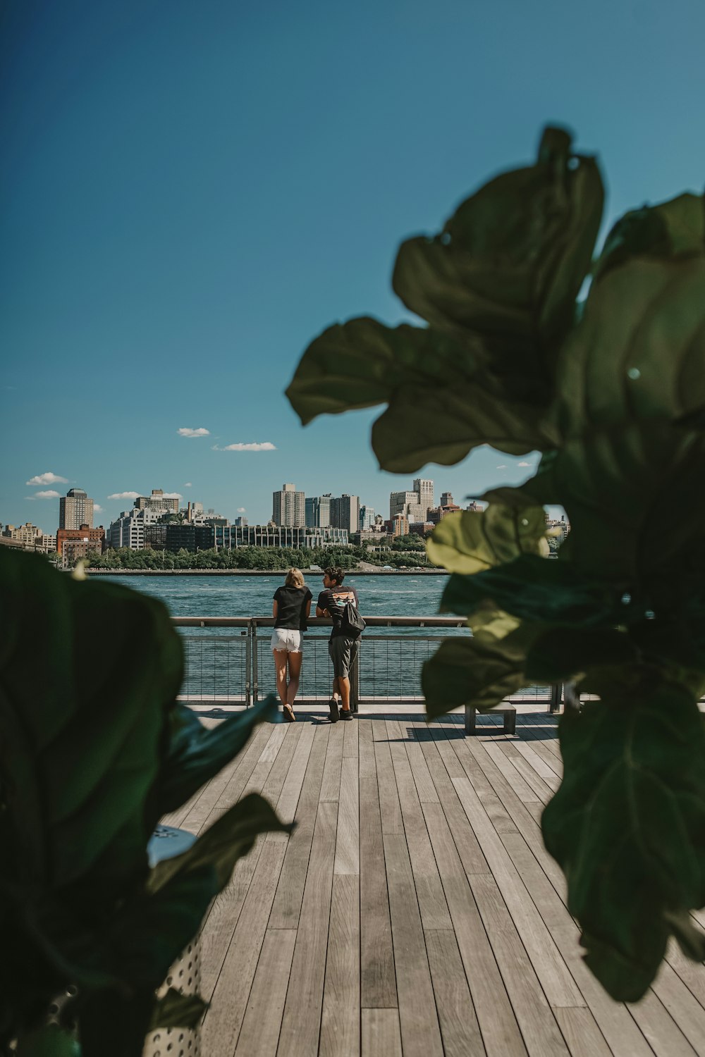 couple standing near railings and body of water
