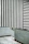 An interior space with minimalist design elements featuring vertical black and white stripes on one wall and horizontal stripes on another. The lower part of the room is lined with light blue and gray tiles, including a small staircase with a metal handrail.