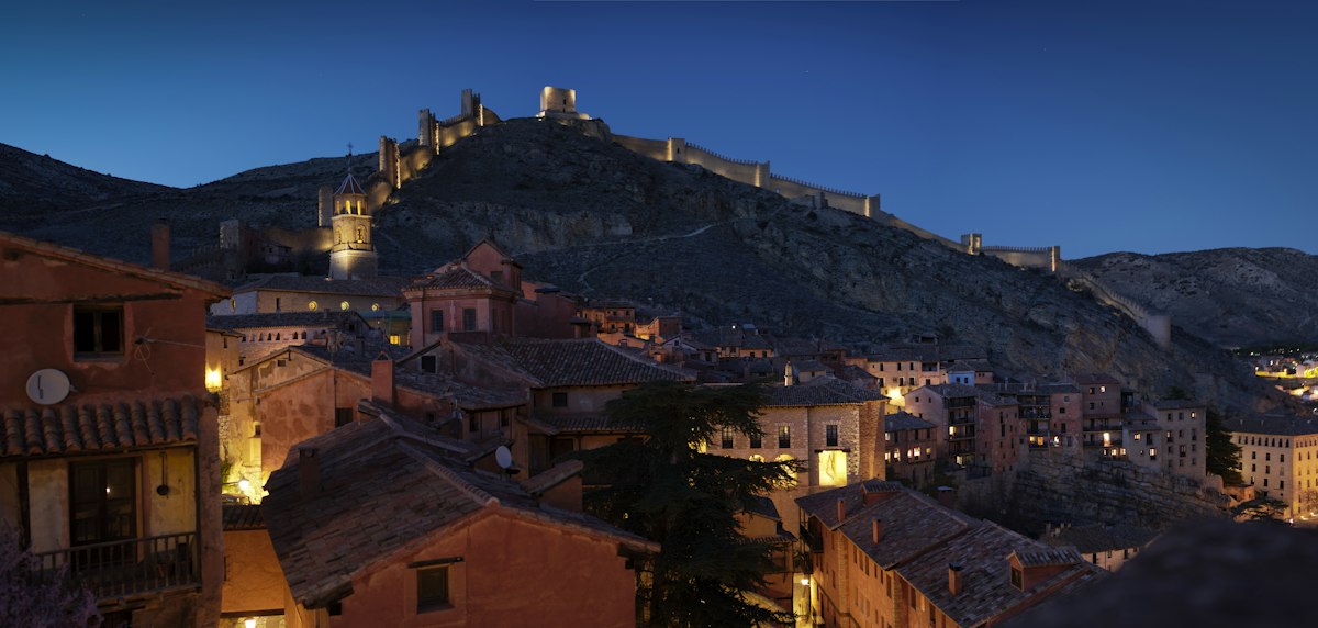Albarracín al anochecer con la muralla iluminada sobre las casas rojizas